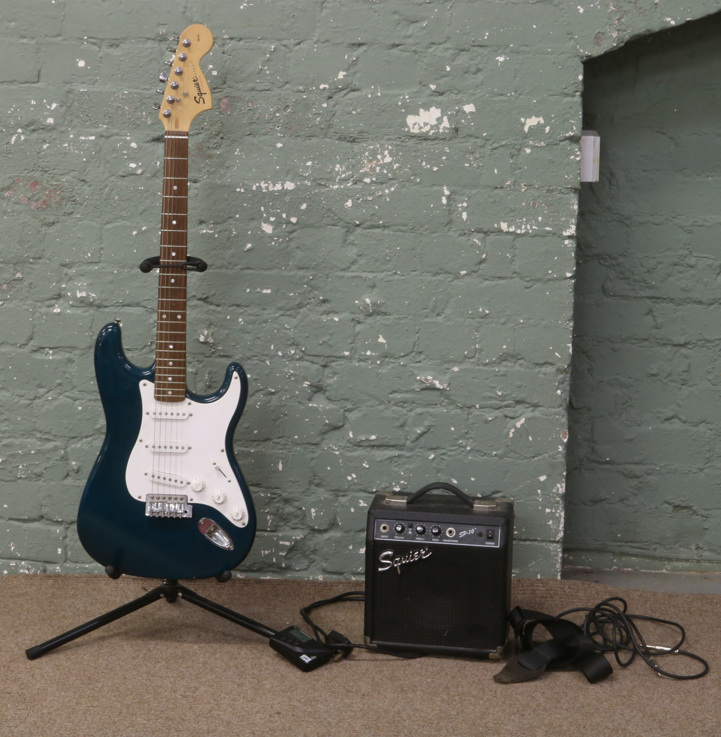 A squire by Fender Stratocaster electric guitar with emerald green body along with a squire SP10