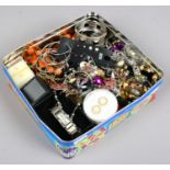 A tin of costume jewellery to include white and yellow metal bracelets, earrings, beads and
