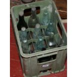 A 12 bottle crate with clear and coloured bottles to include cod and advertising examples.