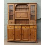 A panelled and glazed pine dresser on bun feet.