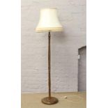 An oak standard lamp and cream shade with circular base.