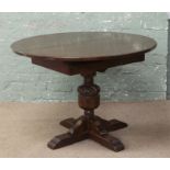 An oak circular extending dining table with carved pineapple centre pedestal support.