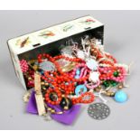 A tin of costume jewellery to include beads, white paste bracelet, clip on earrings etc.