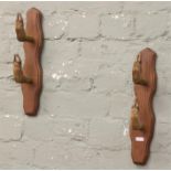 Two taxidermy coat pegs each formed from a pair of deer hooves and mounted on oak plinths.