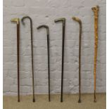 A bundle of walking sticks to include horn handle, brass horse head and metal bound examples.