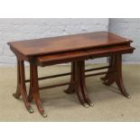 A mahogany nest of three tables with brass paw feet.