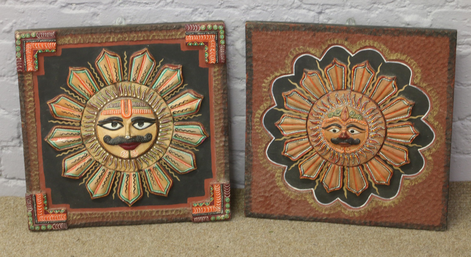 Two decorative wood and plaster wall plaques depicting Hindu sun gods.