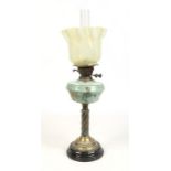 A Victorian brass based oil lamp with opaque glass font enamelled with flowers and having a Vaseline