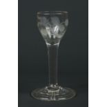 An 18th century wine glass. The bowl etched with a rose and a single flower sprig, raised on a plain