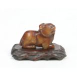 A 19th century Chinese carved soapstone figure of a recumbent beast raised on a hardwood plinth.