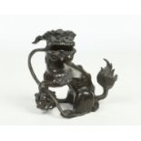 An antique Chinese patinated bronze sculpture of a lion dog guarding a brocade bowl, possibly