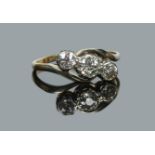A mid 20th century three stone diamond crossover ring. Principal stone approximately 0.4ct, size