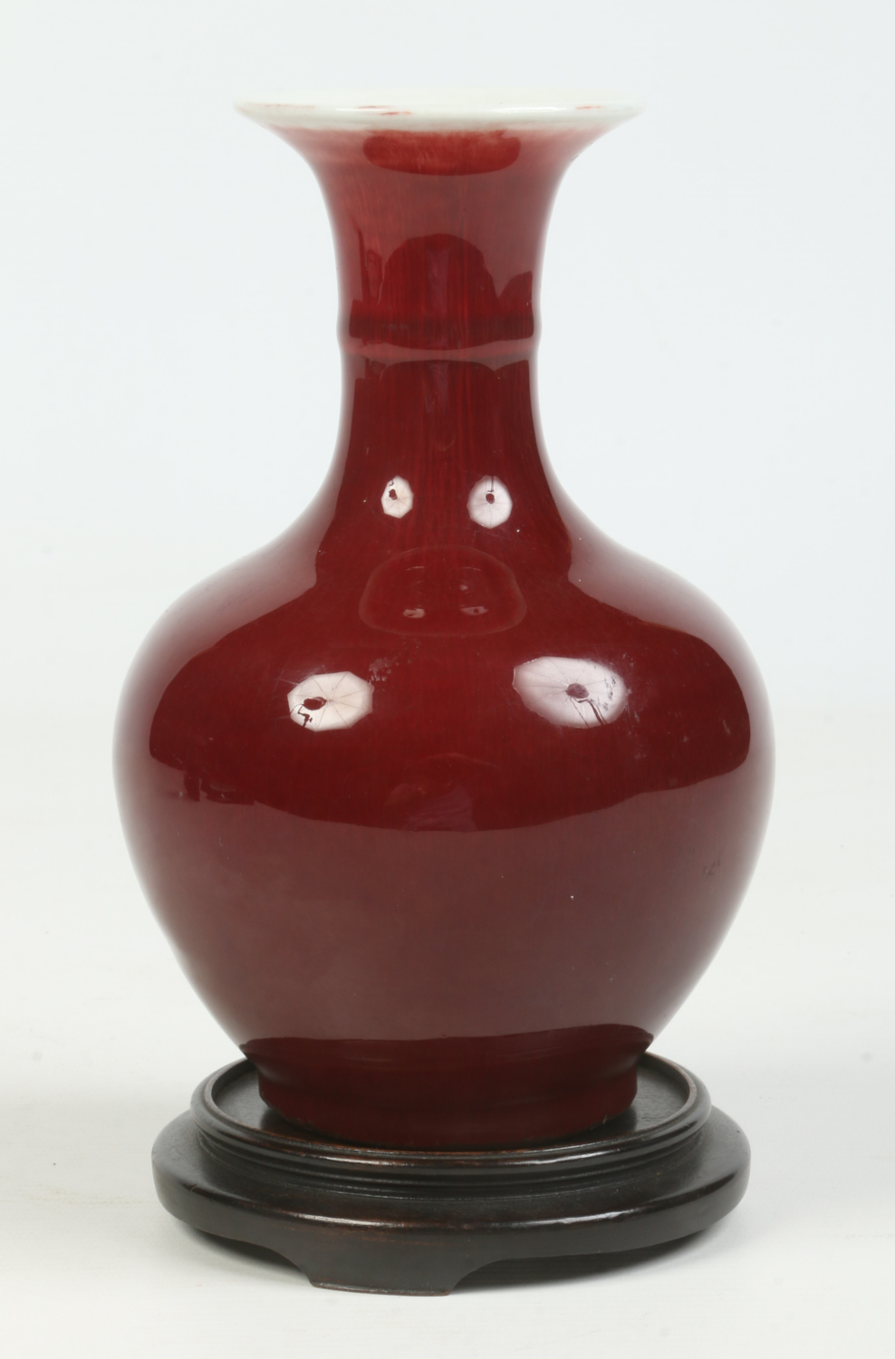 A Chinese small baluster vase on hardwood plinth. With ring moulded neck and decorated in sang de