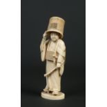 A Japanese Meiji period carved ivory okimono. Formed as a man with a basket upon his head and