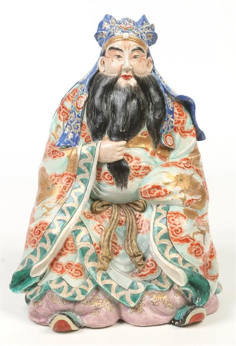A Japanese Meiji period Kutani figure of a seated bearded sage. Wearing a long flowing robe