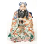A Japanese Meiji period Kutani figure of a seated bearded sage. Wearing a long flowing robe