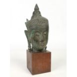 A 19th century Tibetan verdigris bronze bust of Buddha mounted on a later wooden plinth. Formerly