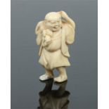 A Japanese Meiji period ivory netsuke. Formed as a man stood holding a sack over one shoulder.