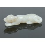 A 19th century Chinese small white jade carving formed as a recumbent dog with charcoal suffusion,