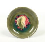 A Moorcroft dish. Green ground and decorated in the Leaves and Berries design. Impressed marks and