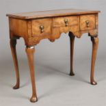 A Georgian walnut lowboy. Quarter veneered, crossbanded and raised on plain cabriole supports,