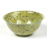 A 20th century Chinese mottled jade bowl of plain turned form and with everted rim, 12.5cm diameter.