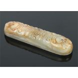 A Chinese mutton fat jade scroll weight of elongated ovoid form. Carved with four stylized fruit