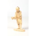 A Japanese Meiji period carved ivory okimono. Formed as a man holding a puffer fish and a bottle,