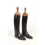 A pair of black leather riding boots, size 9. Along with a pair of wooden boot trees.