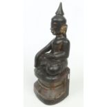 An 18th / 19th century Sino-Tibetan carved and lacquered wooden figure of a seated Buddha raised