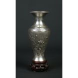 A Chinese silver baluster shaped vase on pierced hardwood plinth. Decorated in relief with prunus