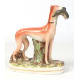 A Victorian Staffordshire pottery model of a hare coursing hound. Gripping a hare in its jaws,