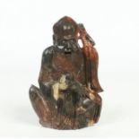 A Chinese carved soapstone figure. Modelled as Shou Lao in seated pose holding a staff and a peach
