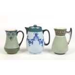 Three James Macintyre jugs. One with a cover ground in pale blue and decorated with tube lined