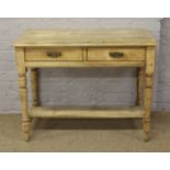 A pine two drawer wash stand raised on circular legs.