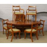 A yew wood twin pedestal extending dining table with extra leaf raised on reeded lion paw feet,