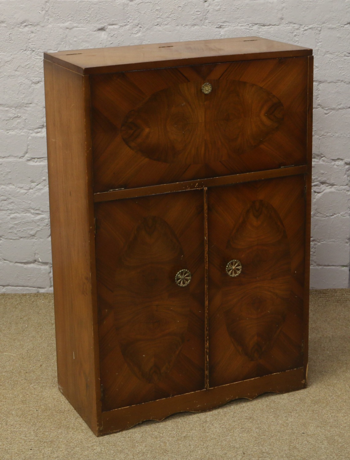 A walnut cocktail cabinet with mirrored interior and cupboard base.