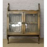 A carved oak wall mount display cupboard with lead glazed doors.