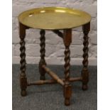 A circular brass top table with barleytwist folding base.