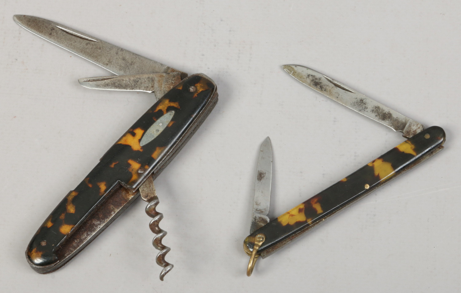 A multi tool pocket knife and another folding pocket knife, both with tortoise shell scales.