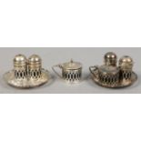 Two silver three part cruet sets each on a pierced silver tray, assayed Birmingham 1931.