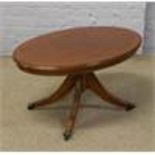 A mahogany oval top coffee table with strung inlay, raised over reeded supports and lion paw feet.