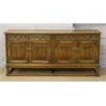 A carved oak sideboard with linen fold decoration raised on turned and square cut legs.