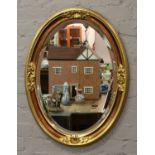 An oval gilt framed bevel edge wall mirror.