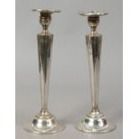 A pair of weighted sterling silver candlesticks of reeded tapering form, engraved and with