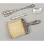 Three silver handled items to include spoon, shoe horn and brush.