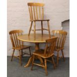 A circular carved oak centre pedestal breakfast table and four slat back kitchen chairs.