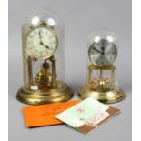 Two Schatz torsion clocks under domes one with a quartz movement the other with damage to its