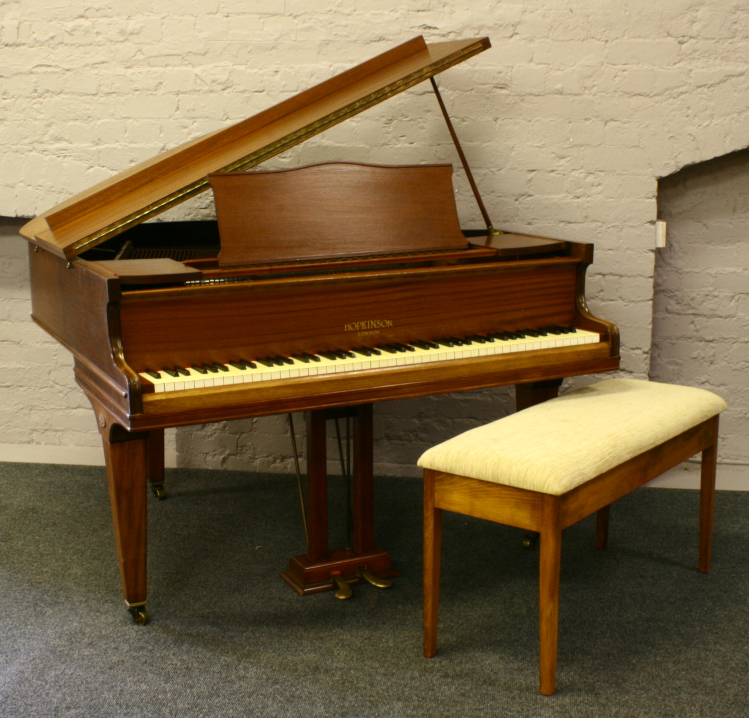 A mahogany baby grand piano raised on square tapering supports, Hopkinson London, along with a