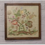 An oak framed embroidery of wooden animals, flowers and leafs.